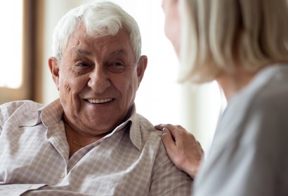 Happy older man feeling relieved after talking to supporting middle aged wife. Smiling elder male patient communicating with nurse. Female medical worker showing professional care and understanding.