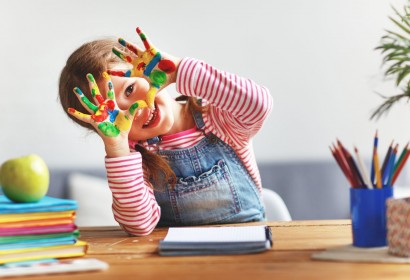 happy funny child girl draws laughing shows hands dirty with paint