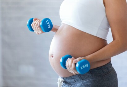 Close-up of pregnant woman doing exercise with dumbbells at home.