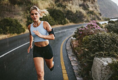 Female athlete running outdoors on highway. Beautiful young woman training running on a rainy day.