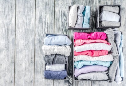 House cleaning concept. Vertical tidying up storage. Marie Kondo tidying method. Neatly folded clothes in the organizer boxes for wardrobe. Wooden background copy space above