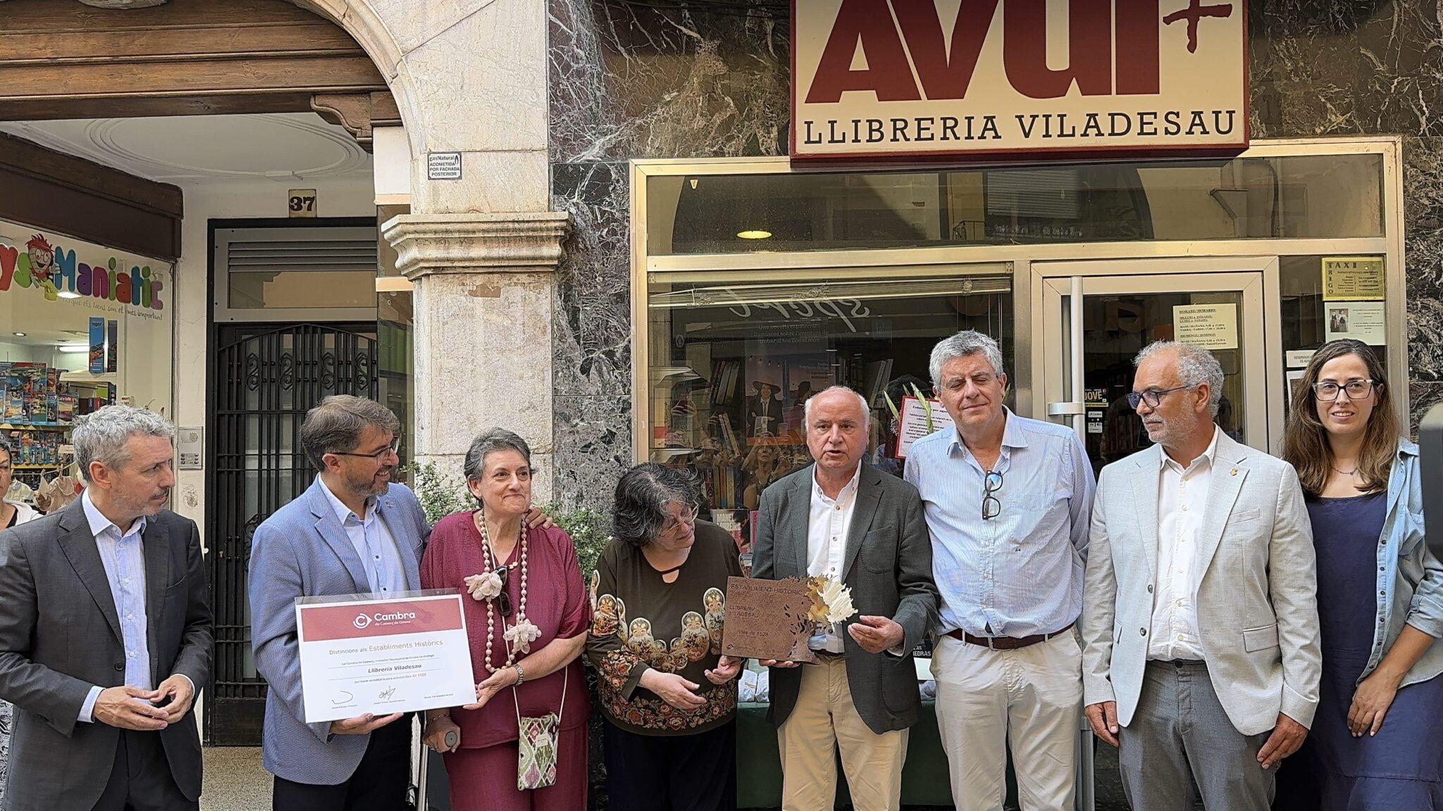 Grup de persones davant de la Llibreria Viladesau durant l'acte de lliurament del Guardó als Establiments Històrics 2025