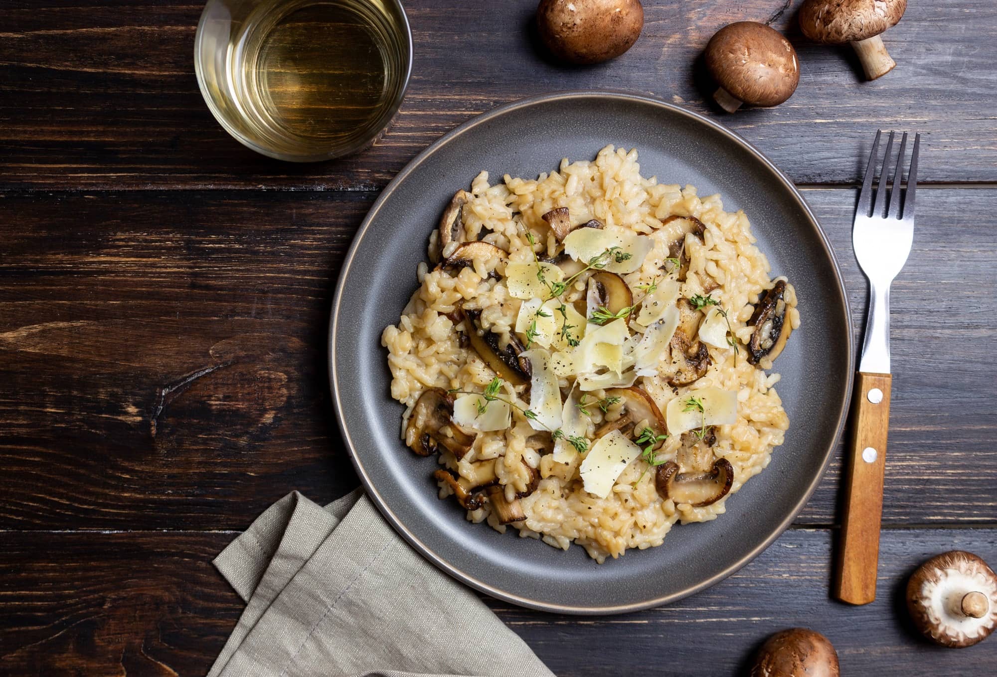 Arròs cremós de bolets servit en un plat fosc amb herbes aromàtiques i bolets saltejats