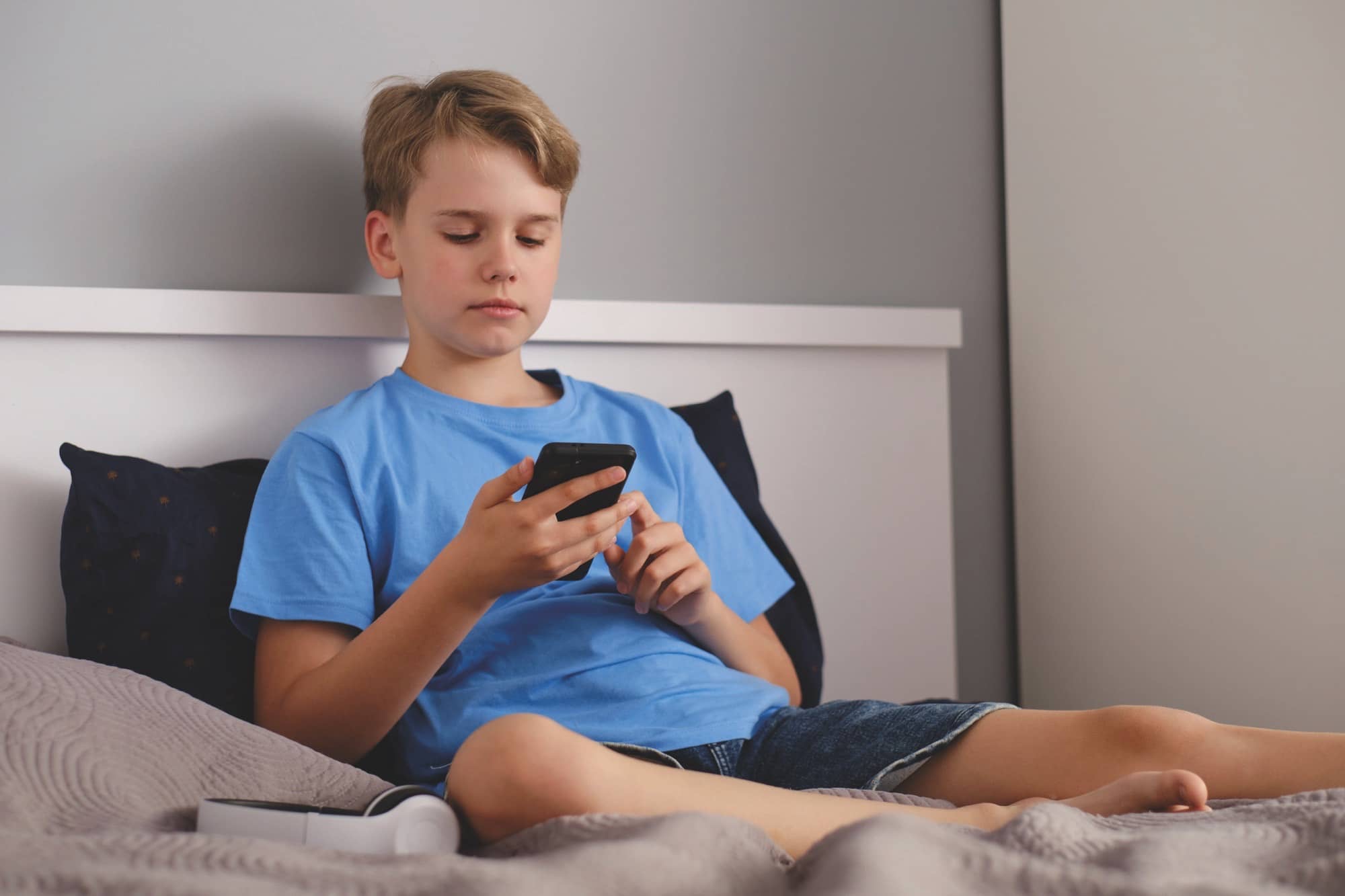 Jove mirant el telèfon mòbil al llit