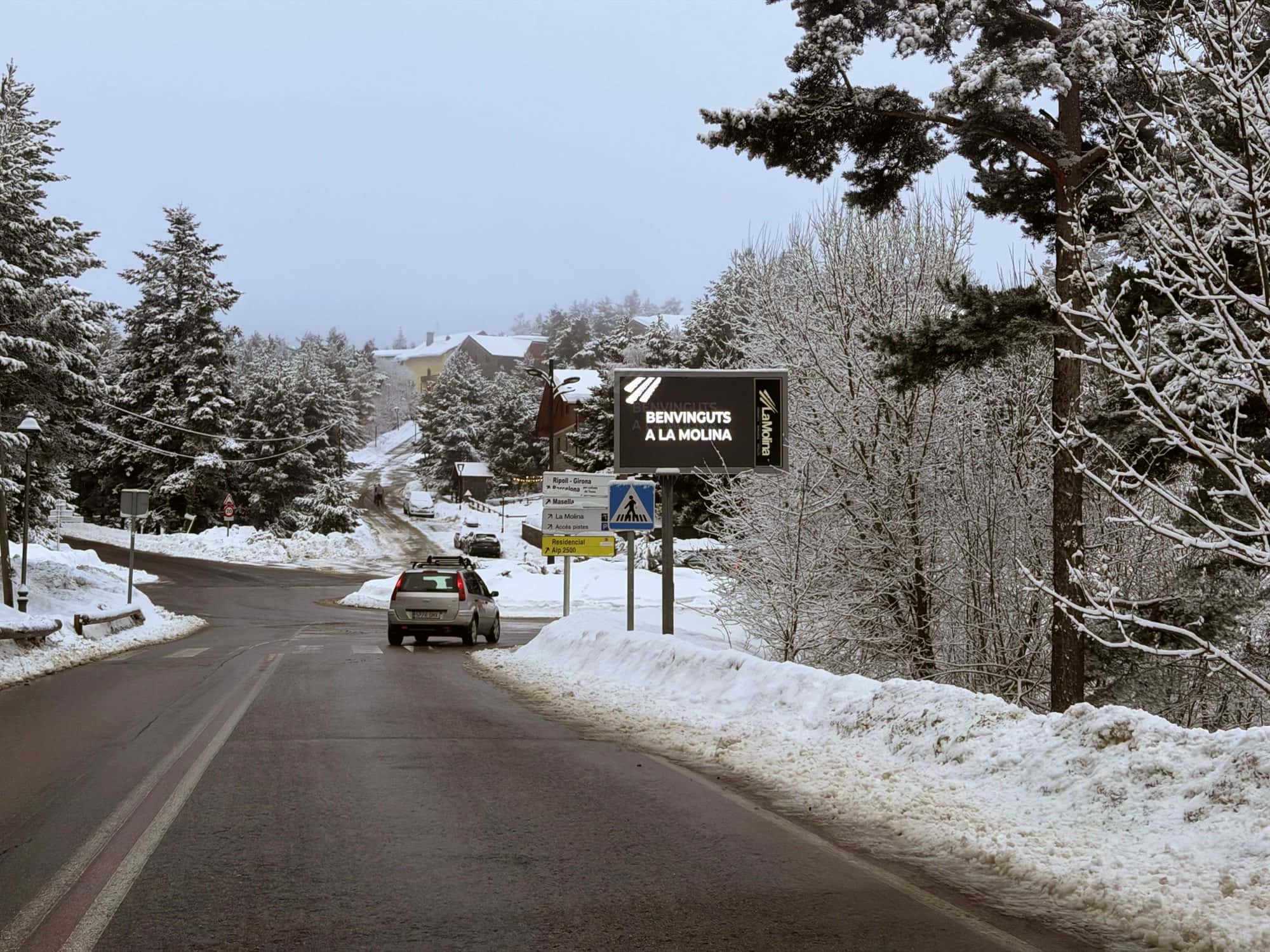 Fotografia d’una carretera en pendent amb el carril humit i els marges coberts de neu