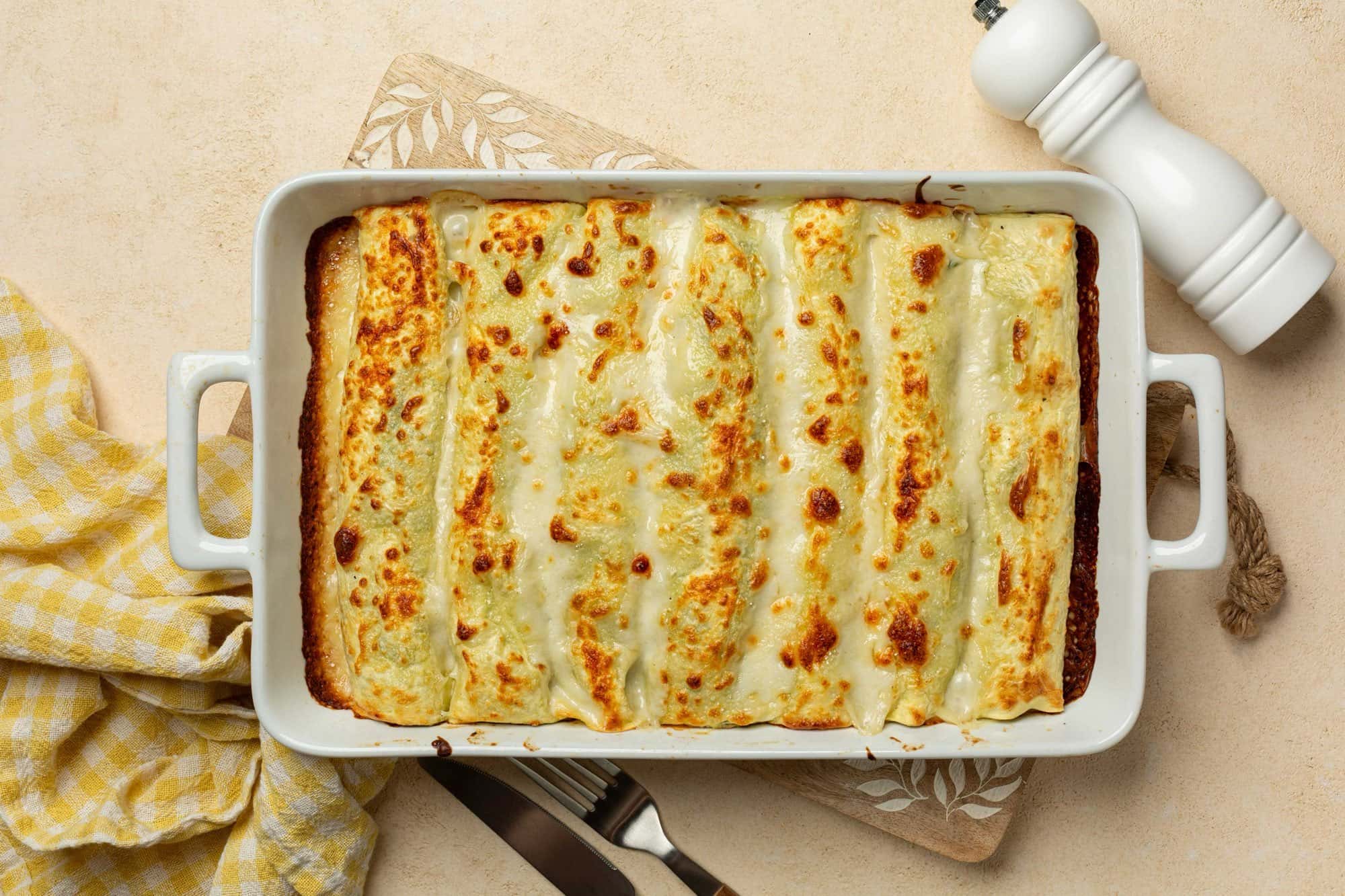 Canelons de bolets i carbassa gratinats en una font de ceràmica blanca