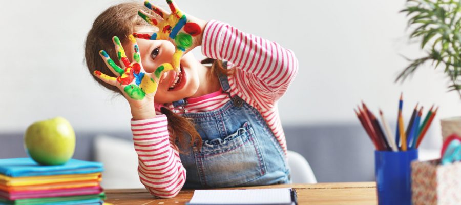 happy funny child girl draws laughing shows hands dirty with paint