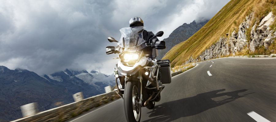 Motorbiker riding in Austrian Alps, dramatic sky. Travel and freedom, outdoor activities