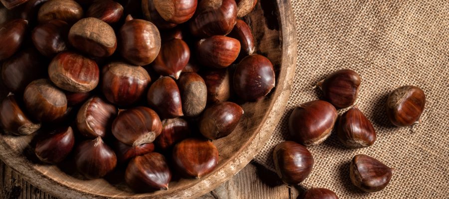 Chestnuts in a wooden plate on a burlap sack.