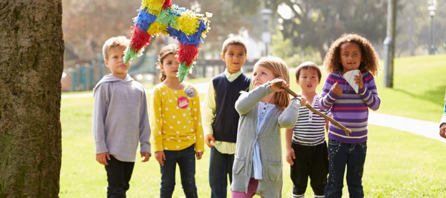 Children Hitting Pinata Hanging From A Tree At Birthday Party