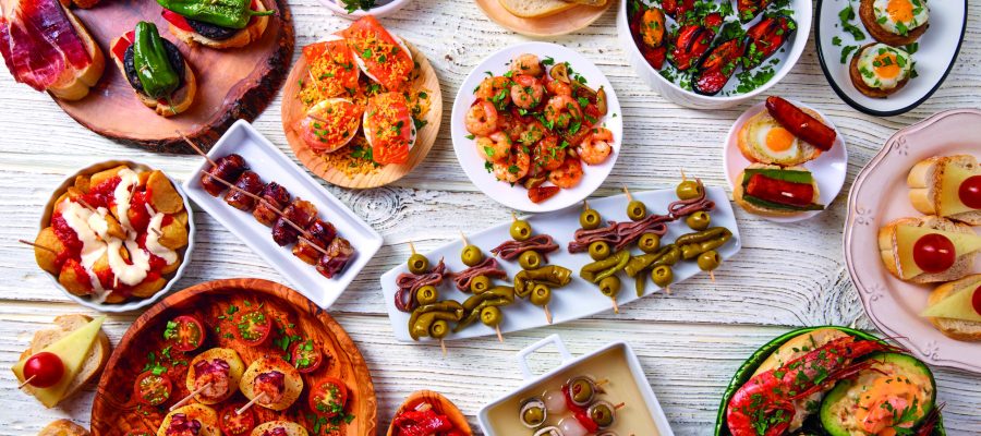 Tapas mix and pinchos food from Spain recipes also pintxos on a white wood board