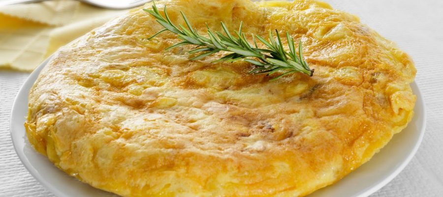 closeup of a plate with a typical tortilla de patatas, spanish omelet, on a set table