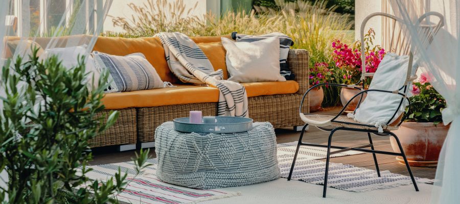 Real photo of an armchair, pouf as a table and wicker couch on a terrace